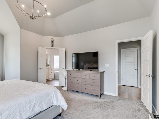 carpeted bedroom with ensuite bath, vaulted ceiling, and a notable chandelier