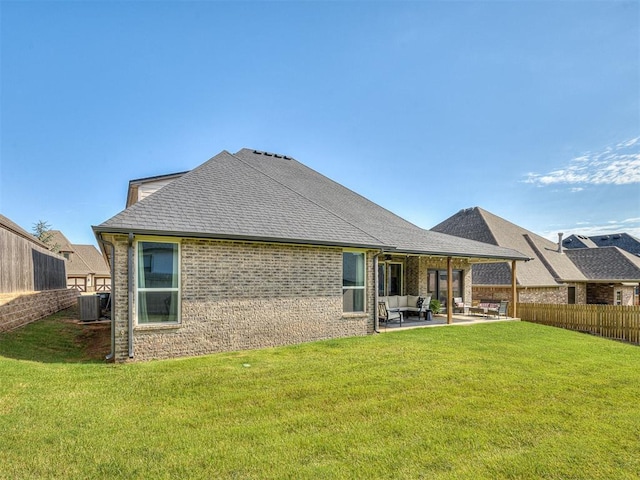 rear view of property with central air condition unit, an outdoor living space, a lawn, and a patio