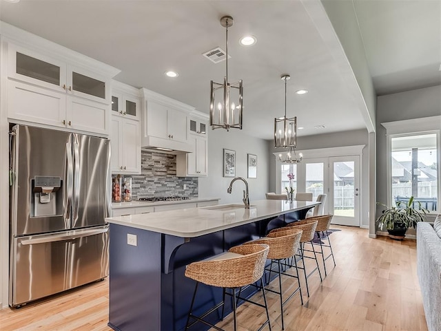 kitchen with white cabinets, appliances with stainless steel finishes, a kitchen island with sink, and sink