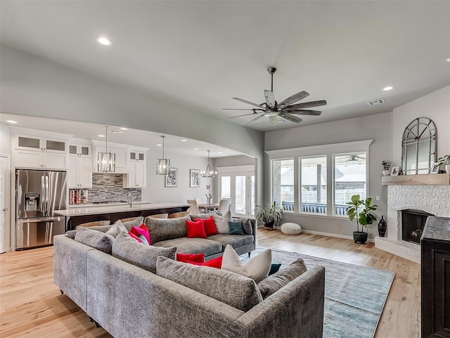 living room with light hardwood / wood-style flooring, ceiling fan, and a stone fireplace