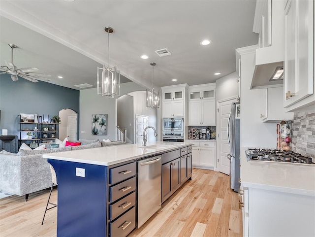 kitchen featuring white cabinets, appliances with stainless steel finishes, light hardwood / wood-style flooring, and a kitchen island with sink