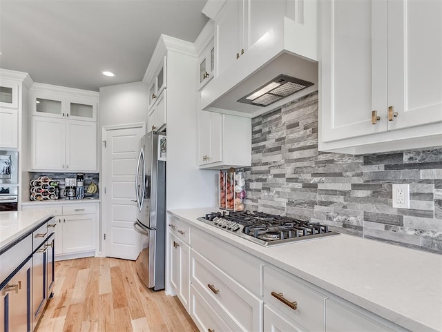 kitchen with tasteful backsplash, premium range hood, stainless steel appliances, light hardwood / wood-style floors, and white cabinetry