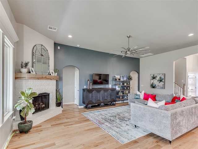 8216 Crew Ln, Edmond, OK 73034 - living room with arched walkways, a ceiling fan, a fireplace, wood finished floors, and recessed lighting