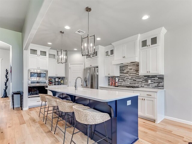 8216 Crew Ln, Edmond, OK 73034 - kitchen with stainless steel appliances, light countertops, backsplash, a chandelier, and a center island with sink