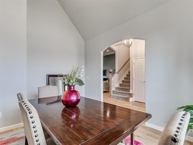 8216 Crew Ln, Edmond, OK 73034 - dining room with arched walkways, stairway, high vaulted ceiling, light wood-style flooring, and a chandelier
