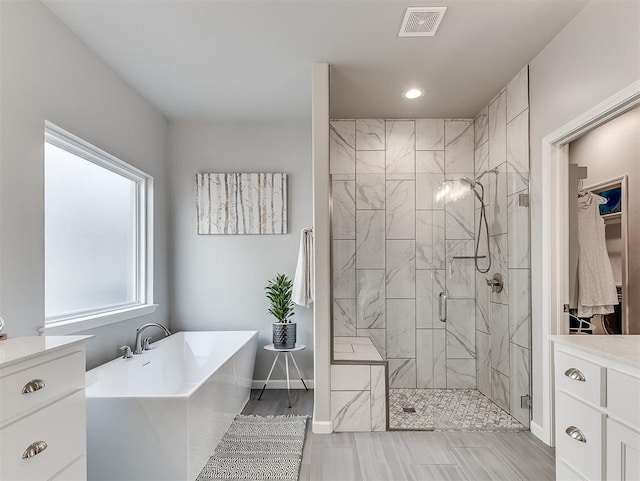 8216 Crew Ln, Edmond, OK 73034 - full bathroom featuring a freestanding bath, a stall shower, recessed lighting, wood finished floors, and vanity