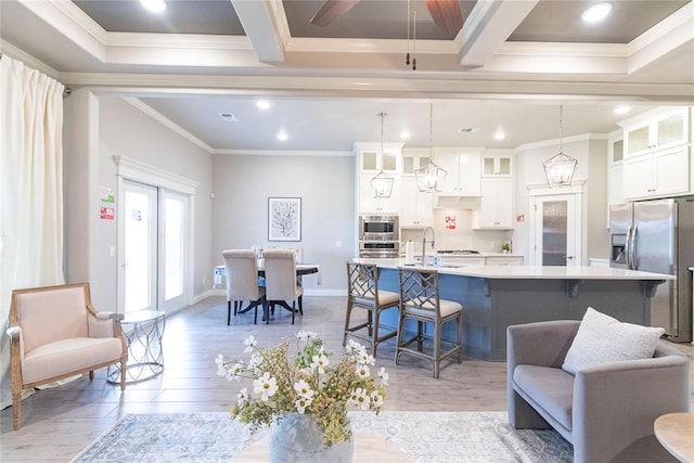 kitchen with white cabinetry, crown molding, an island with sink, and pendant lighting