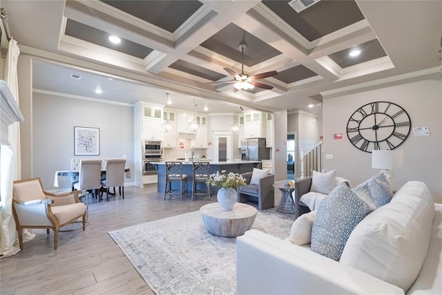 living room featuring light hardwood / wood-style floors, ornamental molding, and coffered ceiling