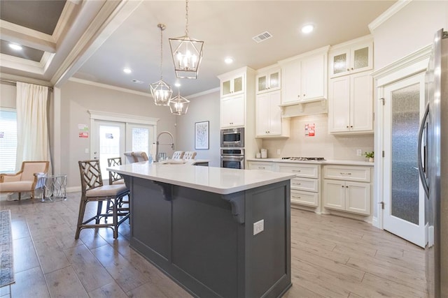 kitchen featuring white cabinetry, a kitchen island with sink, stainless steel appliances, and light wood-type flooring