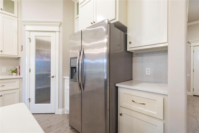 kitchen with white cabinetry, stainless steel refrigerator with ice dispenser, and tasteful backsplash