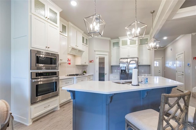 kitchen with a kitchen bar, stainless steel appliances, a kitchen island with sink, sink, and light hardwood / wood-style floors