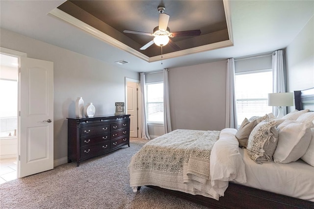 carpeted bedroom with connected bathroom, a tray ceiling, and ceiling fan