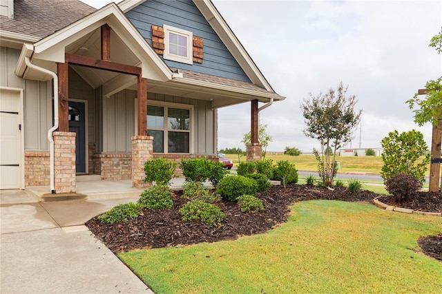 doorway to property with covered porch and a yard