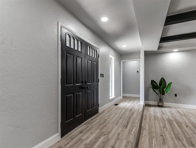 entrance foyer with beamed ceiling and light wood-type flooring