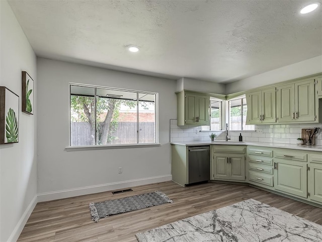 kitchen with backsplash, sink, light hardwood / wood-style flooring, dishwasher, and green cabinets