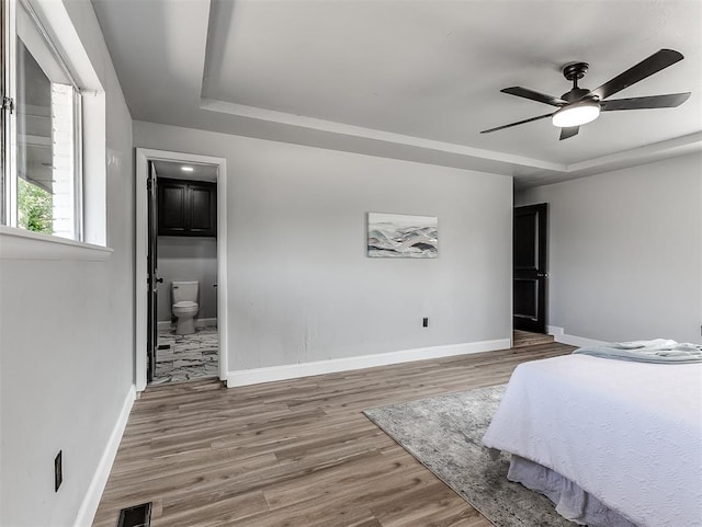 bedroom with hardwood / wood-style flooring, ceiling fan, and connected bathroom