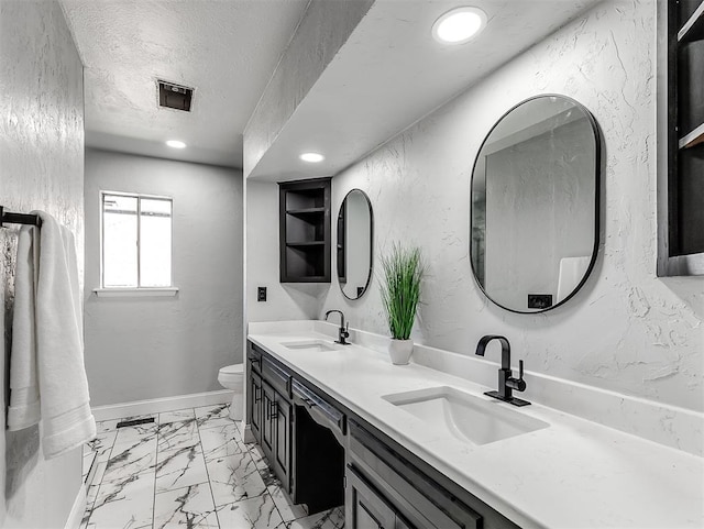 bathroom with built in shelves, vanity, a textured ceiling, and toilet