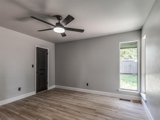 spare room with ceiling fan, plenty of natural light, and light wood-type flooring