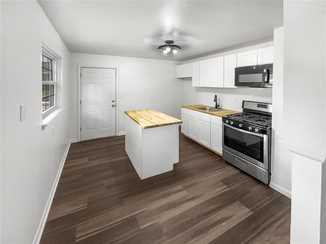 kitchen with wooden counters, white cabinetry, stainless steel range with gas cooktop, and dark wood-type flooring