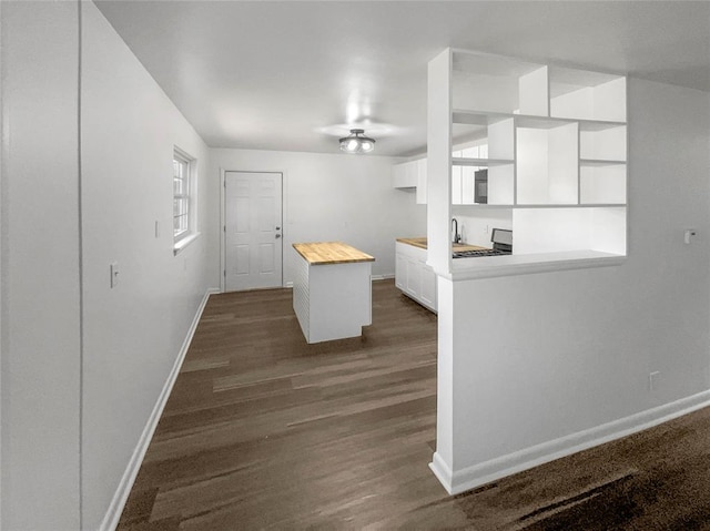 kitchen featuring wood counters, sink, a kitchen island, dark hardwood / wood-style flooring, and white cabinetry