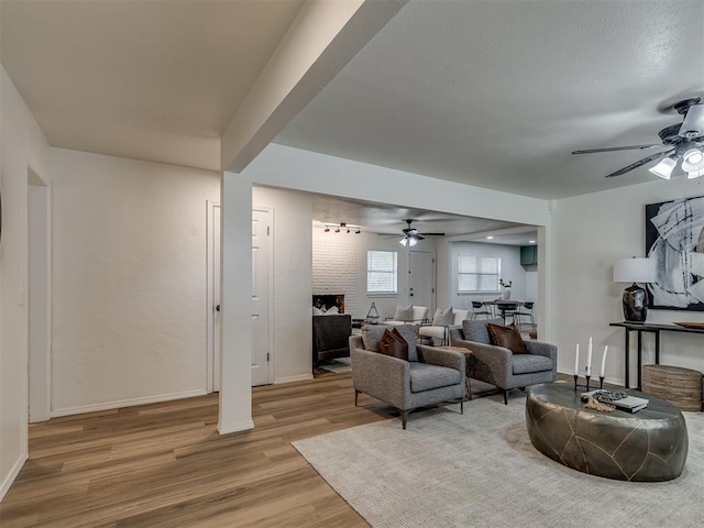 living room featuring light hardwood / wood-style floors, a brick fireplace, and ceiling fan