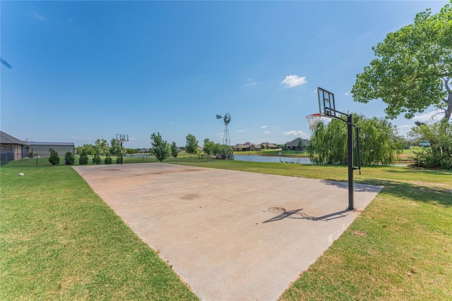 view of sport court with a yard and a water view