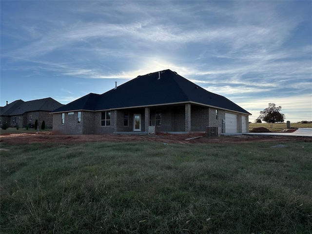 exterior space with a lawn, cooling unit, and a garage