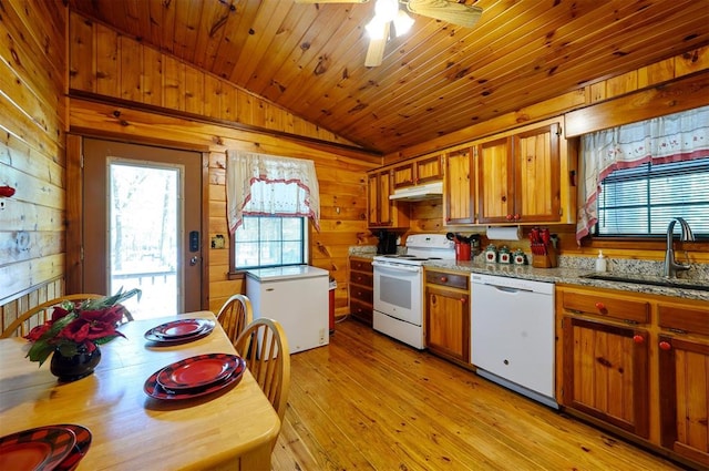 kitchen with white appliances, sink, wooden walls, light hardwood / wood-style flooring, and vaulted ceiling