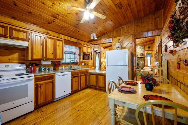 kitchen with sink, light hardwood / wood-style floors, vaulted ceiling, white appliances, and wooden walls