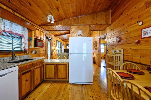 kitchen with wooden walls, sink, a healthy amount of sunlight, and white appliances