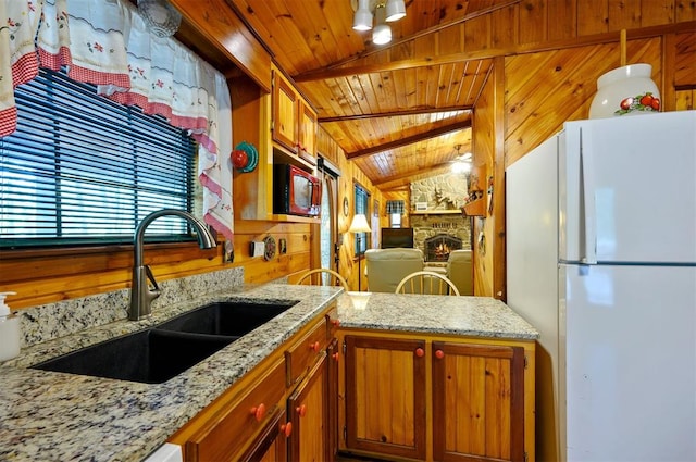 kitchen with lofted ceiling with beams, white refrigerator, sink, a fireplace, and wood ceiling