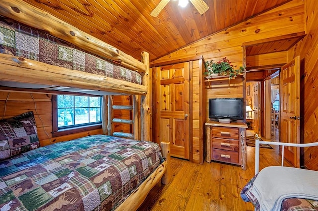 bedroom with ceiling fan, vaulted ceiling, wooden walls, wood ceiling, and light wood-type flooring