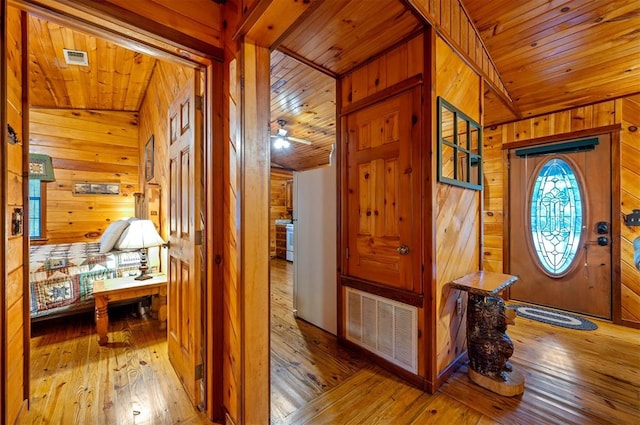 entryway with wood walls, light hardwood / wood-style flooring, ceiling fan, and wooden ceiling