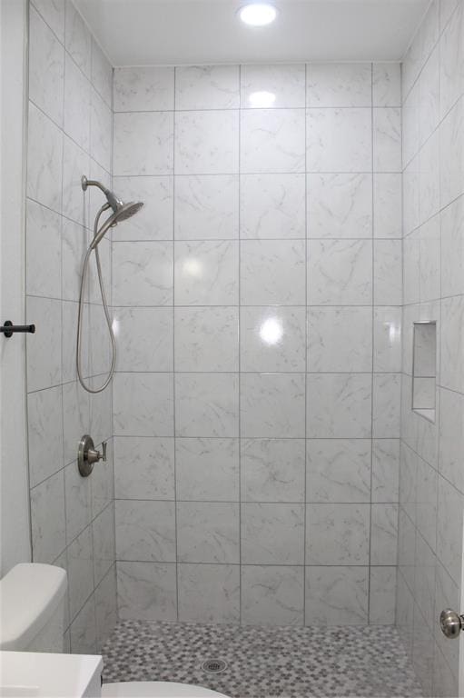 bathroom with a tile shower and toilet