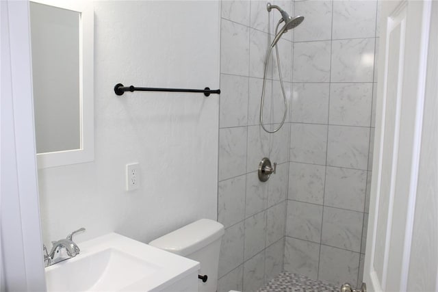 bathroom with tiled shower, toilet, and sink