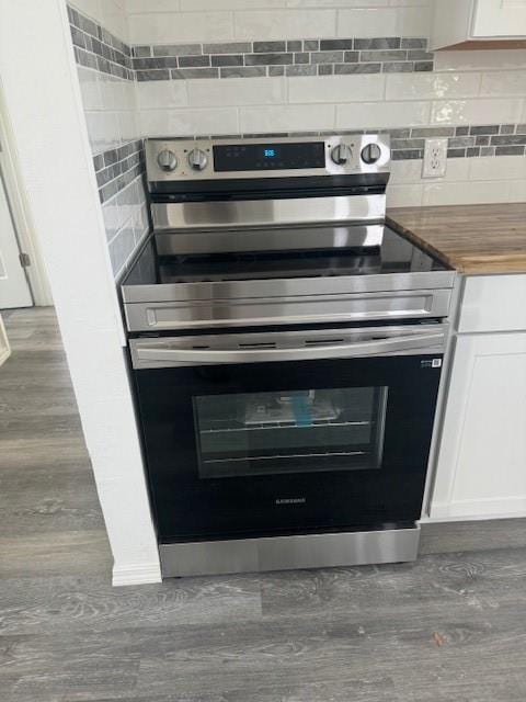 interior details featuring white cabinets, decorative backsplash, and stainless steel range with electric cooktop