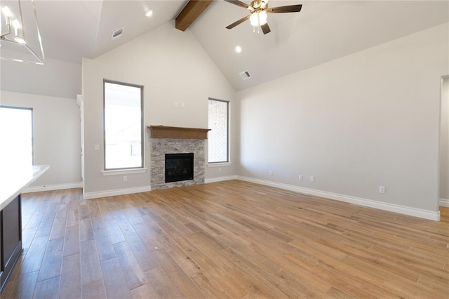 unfurnished living room with beam ceiling, high vaulted ceiling, light hardwood / wood-style flooring, ceiling fan, and a fireplace