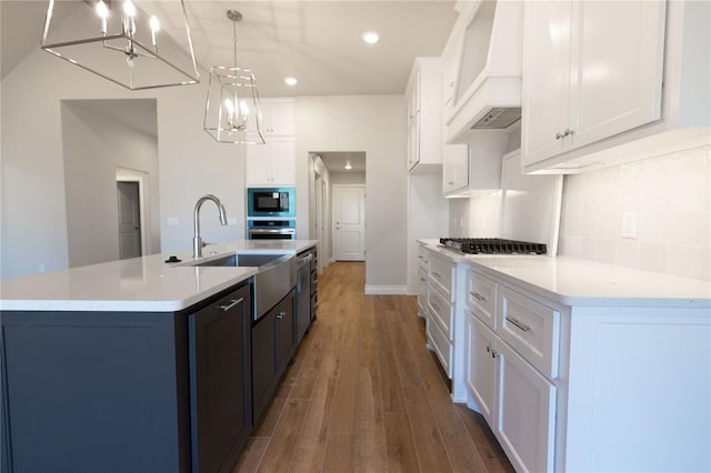 kitchen with stainless steel appliances, an island with sink, hanging light fixtures, and white cabinets