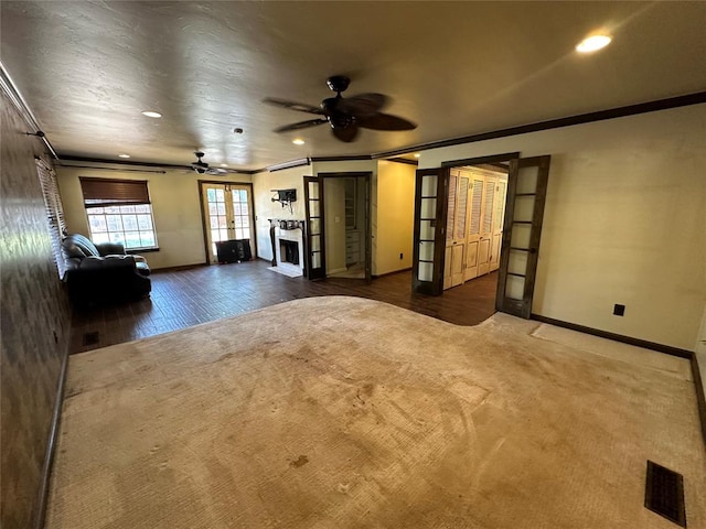 unfurnished living room featuring ceiling fan, dark hardwood / wood-style flooring, crown molding, and french doors