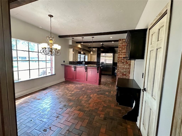 kitchen with sink, hanging light fixtures, kitchen peninsula, built in refrigerator, and a chandelier