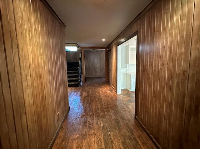 corridor with wooden walls and dark wood-type flooring