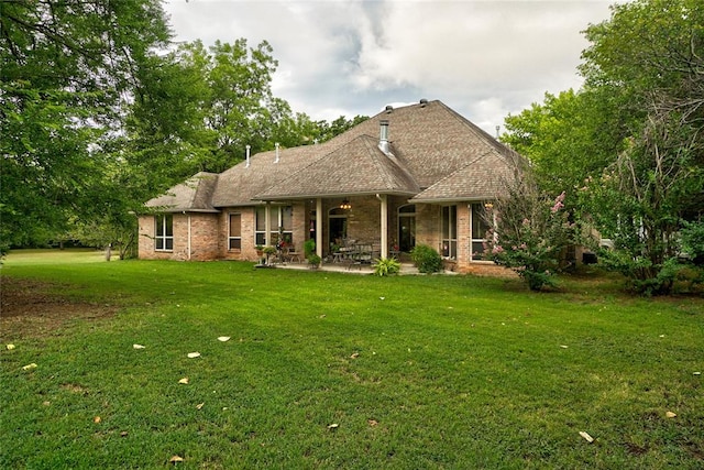 rear view of house with a lawn and a patio