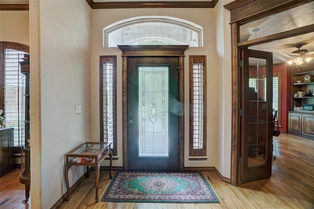 entrance foyer featuring plenty of natural light, light hardwood / wood-style floors, crown molding, and ceiling fan