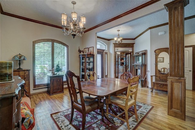 dining space featuring crown molding, light hardwood / wood-style flooring, and decorative columns