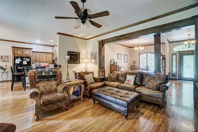 living room featuring a textured ceiling, light wood-type flooring, ornate columns, and crown molding