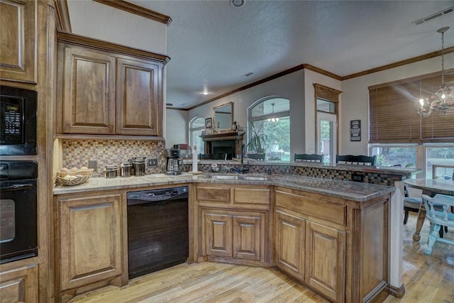 kitchen featuring tasteful backsplash, sink, black appliances, a notable chandelier, and light hardwood / wood-style floors