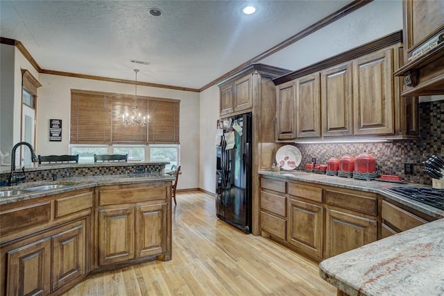 kitchen featuring black fridge, custom exhaust hood, sink, an inviting chandelier, and light hardwood / wood-style floors