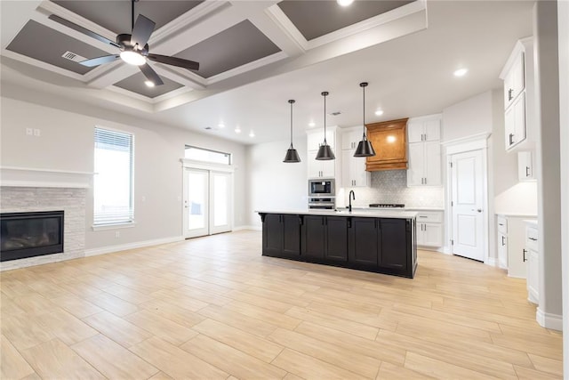 kitchen featuring ceiling fan, tasteful backsplash, light countertops, open floor plan, and built in microwave