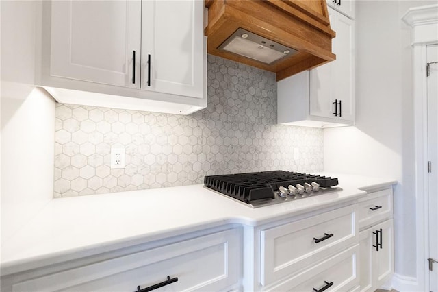 kitchen with tasteful backsplash, white cabinets, stainless steel gas cooktop, custom exhaust hood, and light countertops