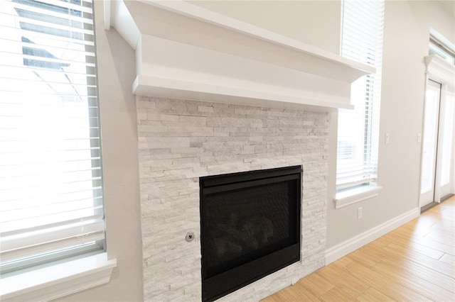 interior details featuring a stone fireplace, wood finished floors, and baseboards